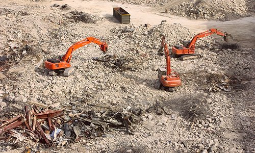 several pieces of equipment sorting construction debris into piles for reuse